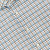 A close-up of the Check Twill Slim Dress Shirt by ETON, showcasing its slim fit design and plaid pattern in light blue, tan, white, and orange. Crafted from wrinkle-resistant organic cotton, this dress shirt features a light blue checkered print with four white buttons visible along with part of the collar and the signature ETON label.