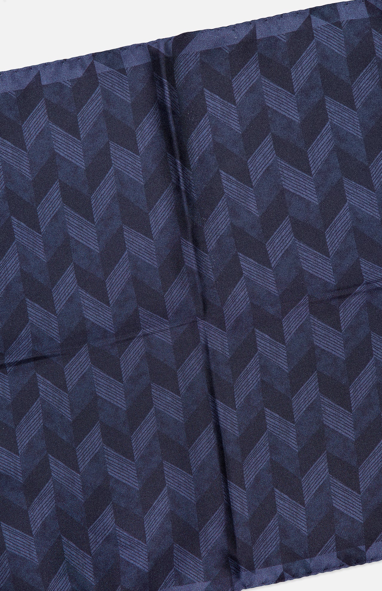 A folded piece of fabric with a repeating chevron pattern in various shades of dark blue, the ETON Chevron Silk Twill Pocket Square features a subtle texture and visible creases along the center, making it an ideal luxury men's accessory. This silk twill pocket square adds a refined touch to any ensemble.