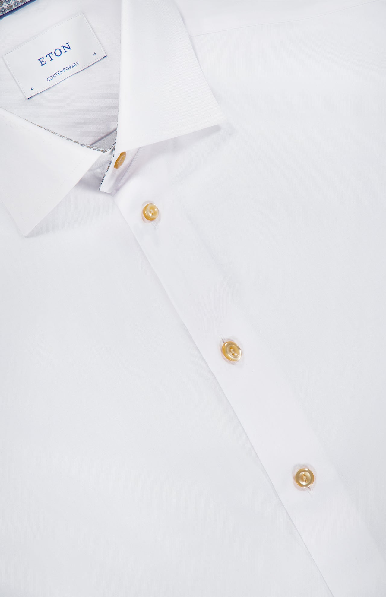 A close-up of the Geometric Effect Signature Twill Slim Shirt by ETON, showcasing its contemporary slim fit in wrinkle-resistant cotton, gold buttons, and subtle geometric-patterned lining inside the collar.
