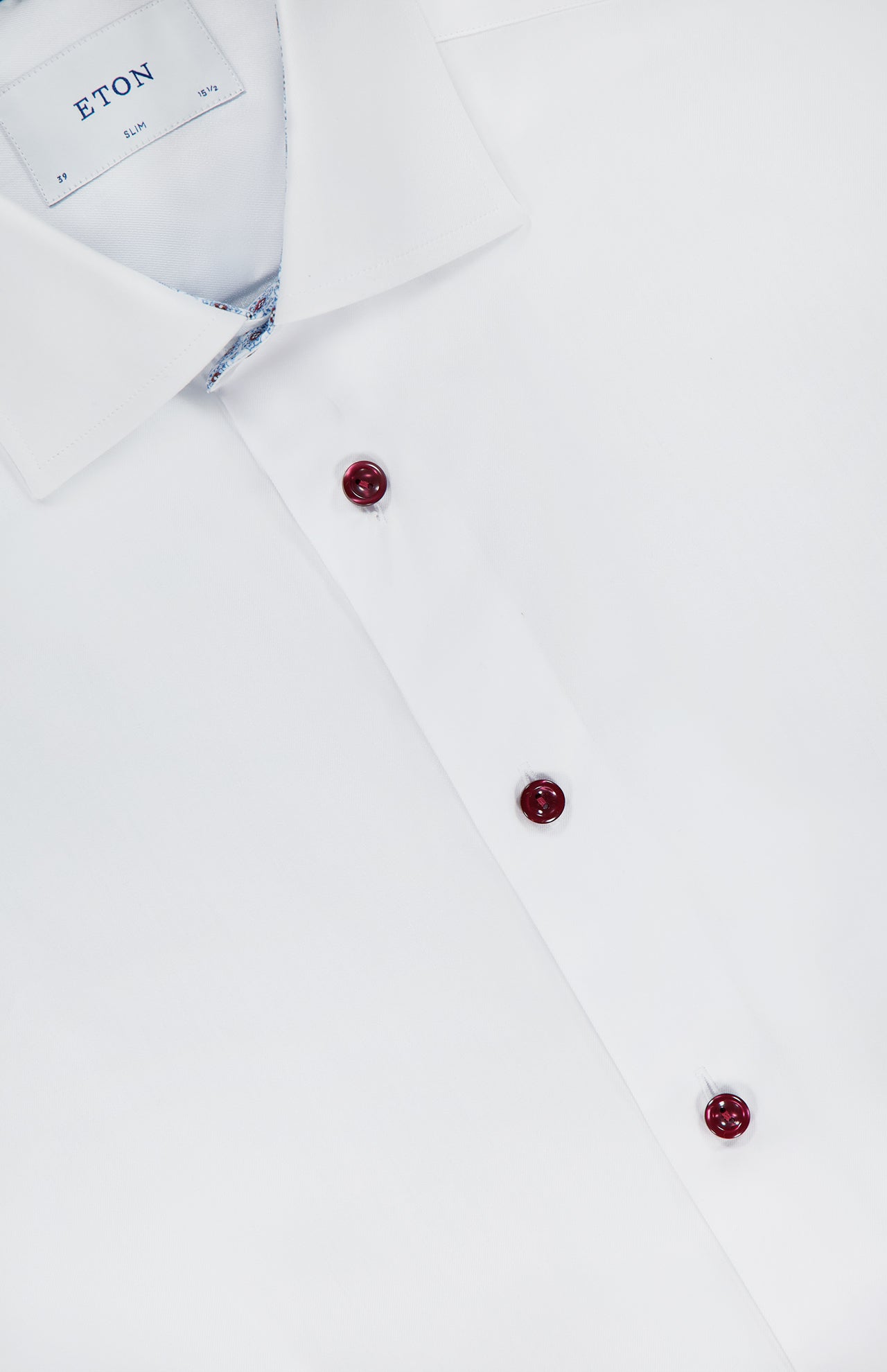 A close-up of the ETON Geometric Effect Twill Contemporary Dress Shirt in white, featuring a spread collar, three maroon buttons, subtle patterned collar lining, and wrinkle-resistant fabric for all-day crispness.
