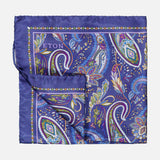 The ETON Paisley Silk Twill Pocket Square is a luxurious accessory crafted from fine silk, showcasing a vibrant blue background decorated with intricate paisley patterns in green, purple, yellow, and white. The brand name "ETON" is elegantly displayed in one corner of this distinguished blue silk pocket square.