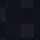 The Patchwork Merino Wool Scarf from ETON features dark fabric with a subtle checkered pattern, pairing alternating squares of solid black with squares adorned with tiny white dots for a textured, woven look reminiscent of a classic wool scarf.