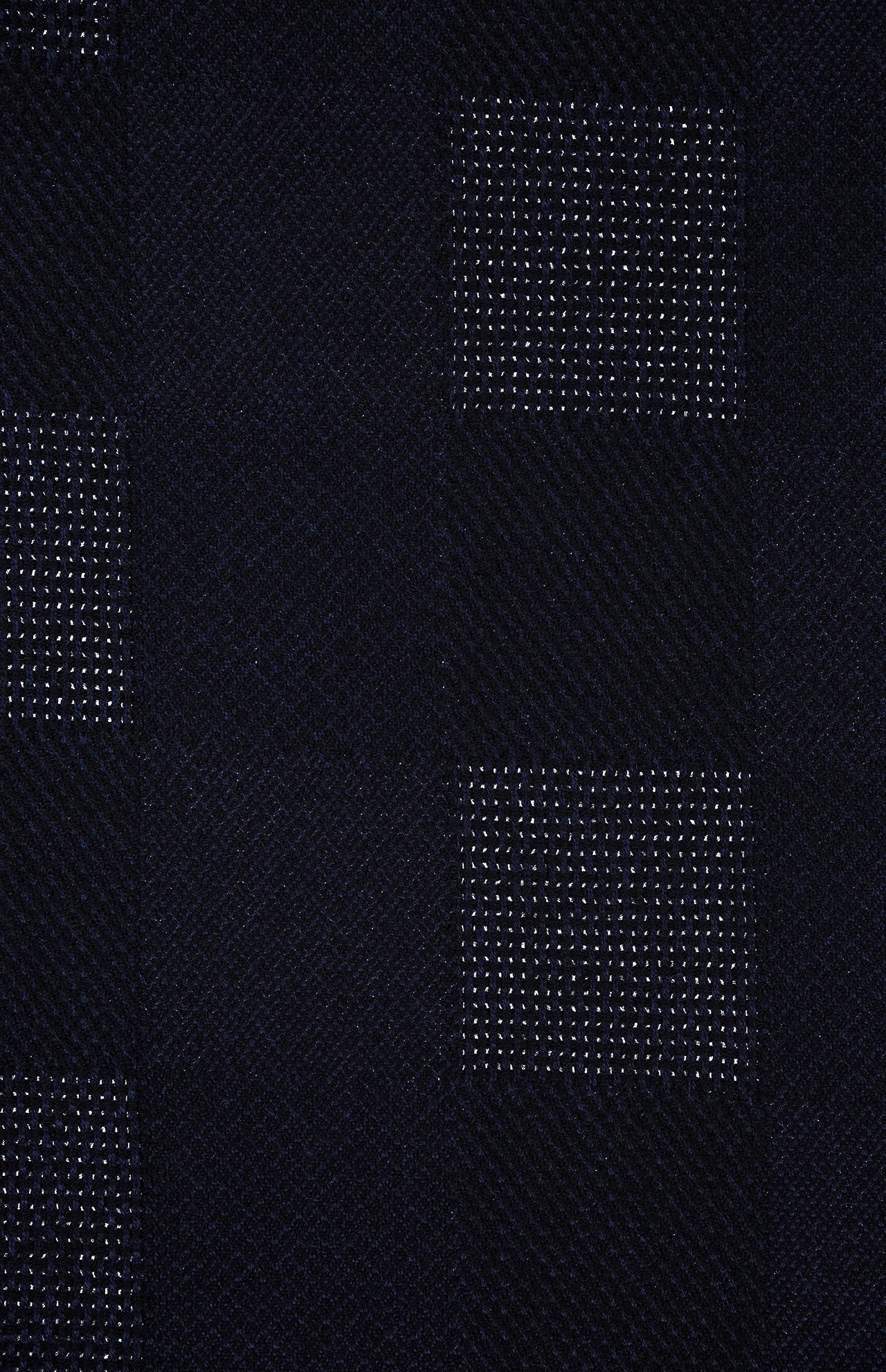 The Patchwork Merino Wool Scarf from ETON features dark fabric with a subtle checkered pattern, pairing alternating squares of solid black with squares adorned with tiny white dots for a textured, woven look reminiscent of a classic wool scarf.