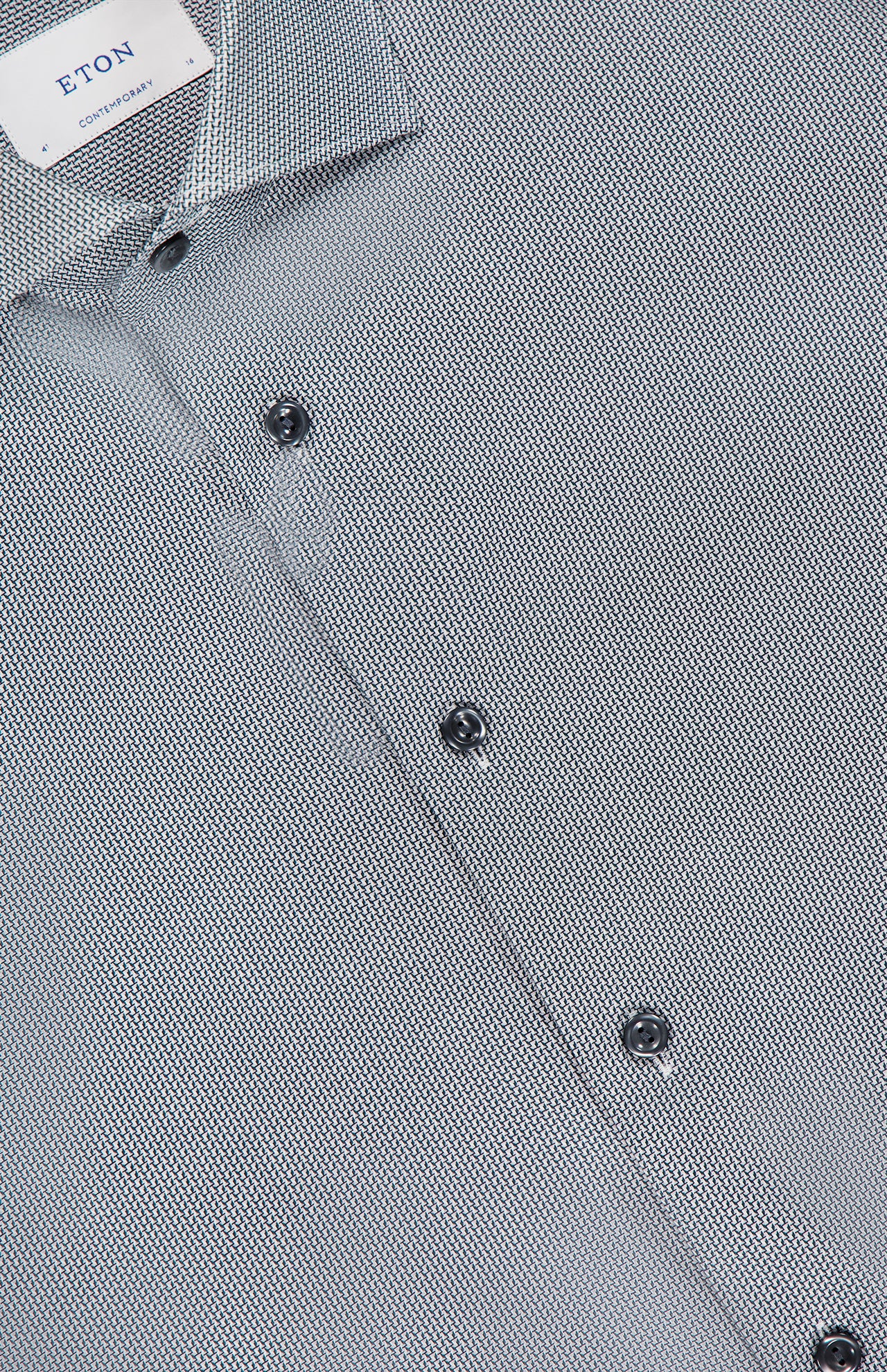 Close-up of the ETON Semi Solid Dobby Contemporary Dress Shirt with black buttons and a visible collar label. The wrinkle-resistant fabric displays a small geometric pattern in white and dark gray.