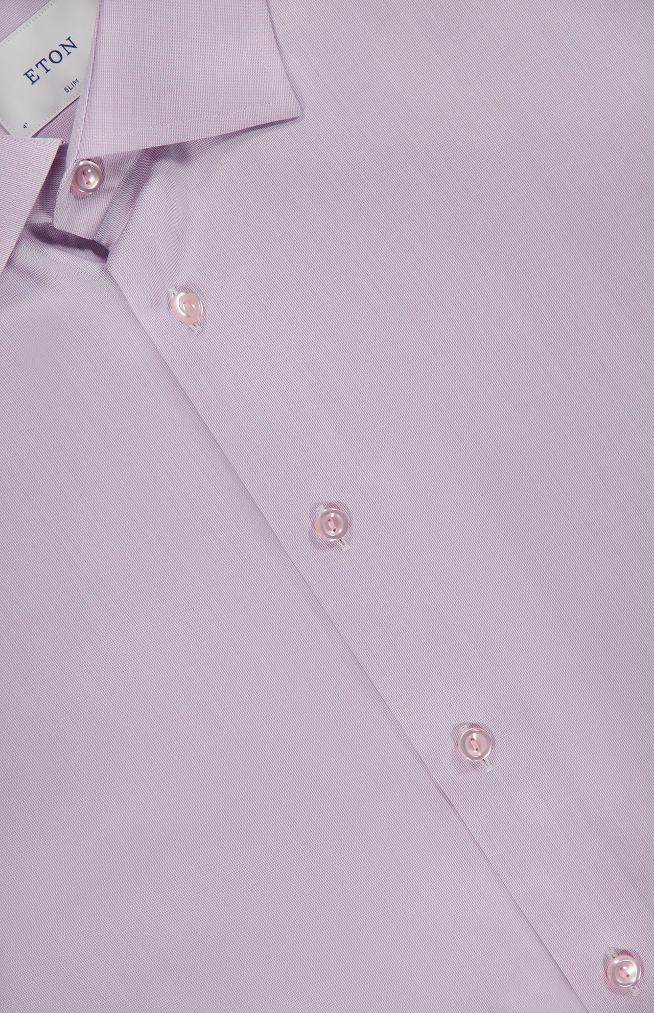 Close-up of ETON's Semi Solid Signature Twill Dress Shirt in light pink, featuring a slim fit, classic collar, white buttons, and a smooth texture. The inside collar displays the ETON label.