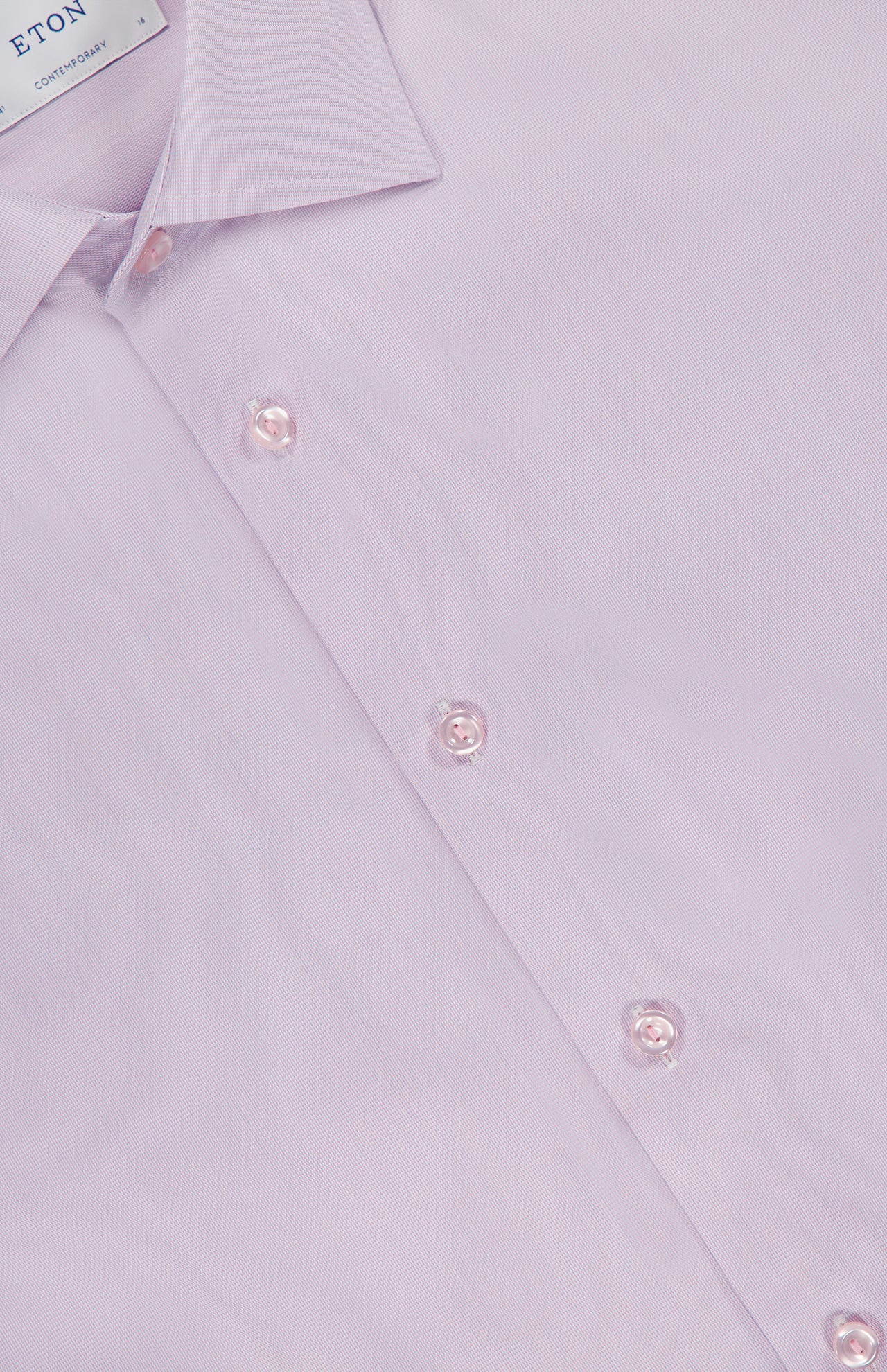 A close-up of ETON’s Semi Solid Signature Twill Dress Shirt, featuring a classic collar and pink buttons on pale pink organic cotton with a smooth, finely textured finish. The label inside the collar displays the ETON brand.