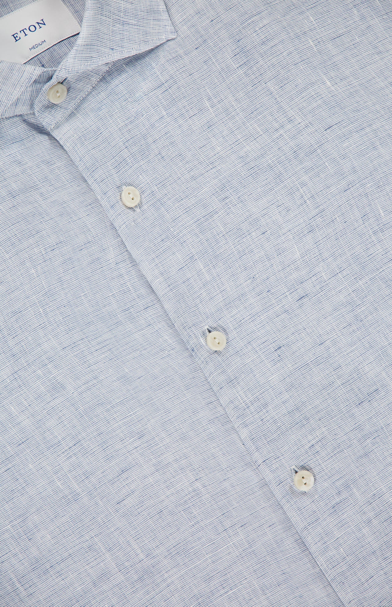 Close-up of ETON's Solid Linen Dress Shirt in pale blue, with white buttons and a subtly textured fabric. The image highlights the collar and upper chest, emphasizing the classic linen weave and refined style.