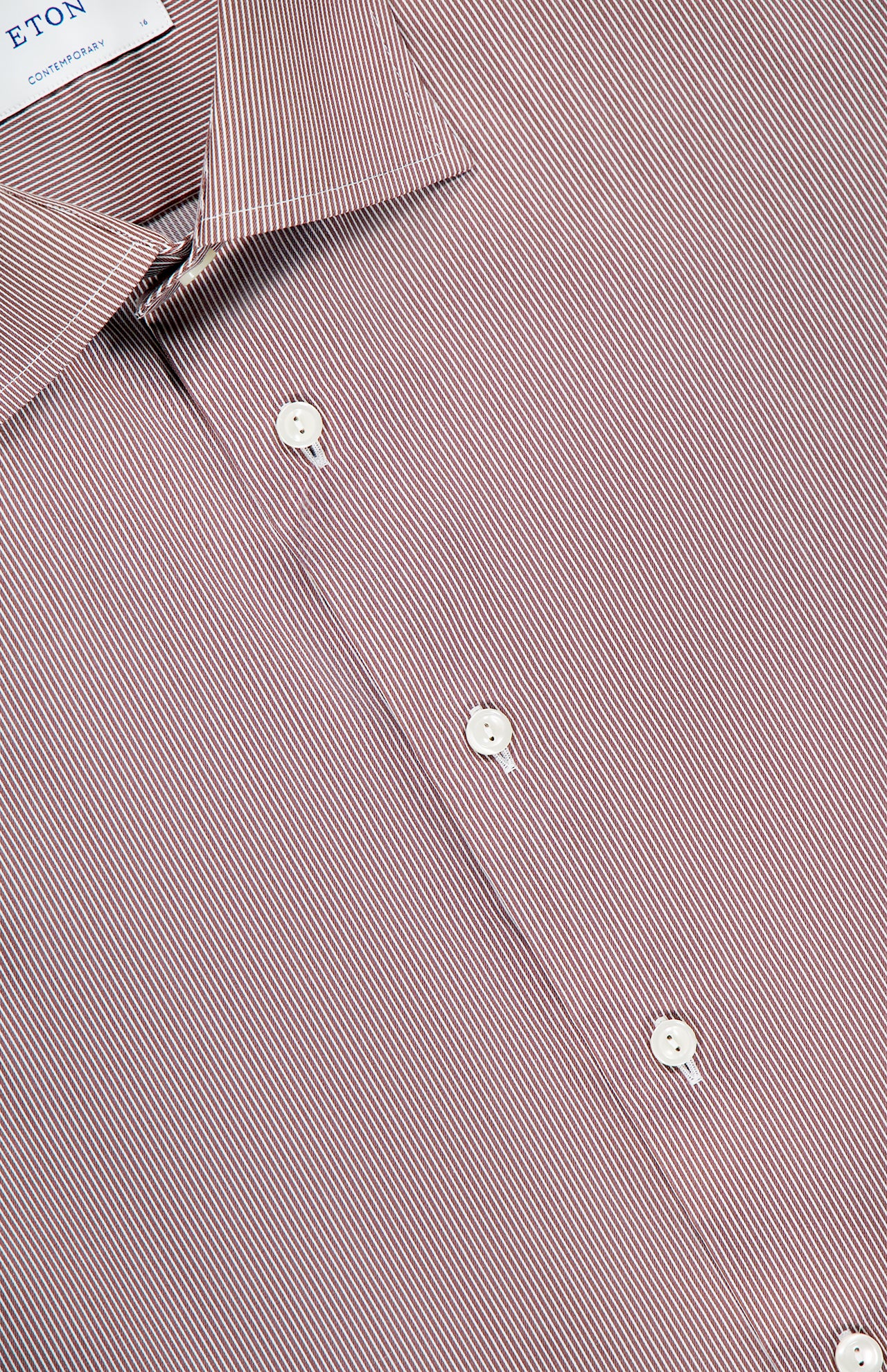 Close-up of the ETON Striped Fine Twill Contemporary Dress Shirt, featuring thin diagonal red and white stripes, white buttons, and a pointed collar with an ETON label.