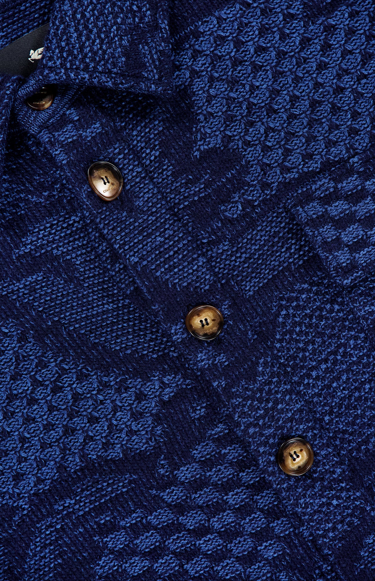 Close-up of the ETRO Knitted Pattern Jacket, showcasing a blue textured fabric with a geometric pattern and four brown buttons on the front placket, reflecting refined Italian craftsmanship.