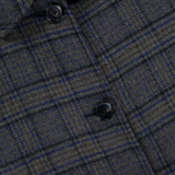 Close-up of the ETRO Plaid Long Reversible Coat, a men’s Italian design crafted from plaid fabric in dark green and navy blue with lighter accents. Four black buttons are arranged in a vertical line, highlighting the texture and rich detail of the material.