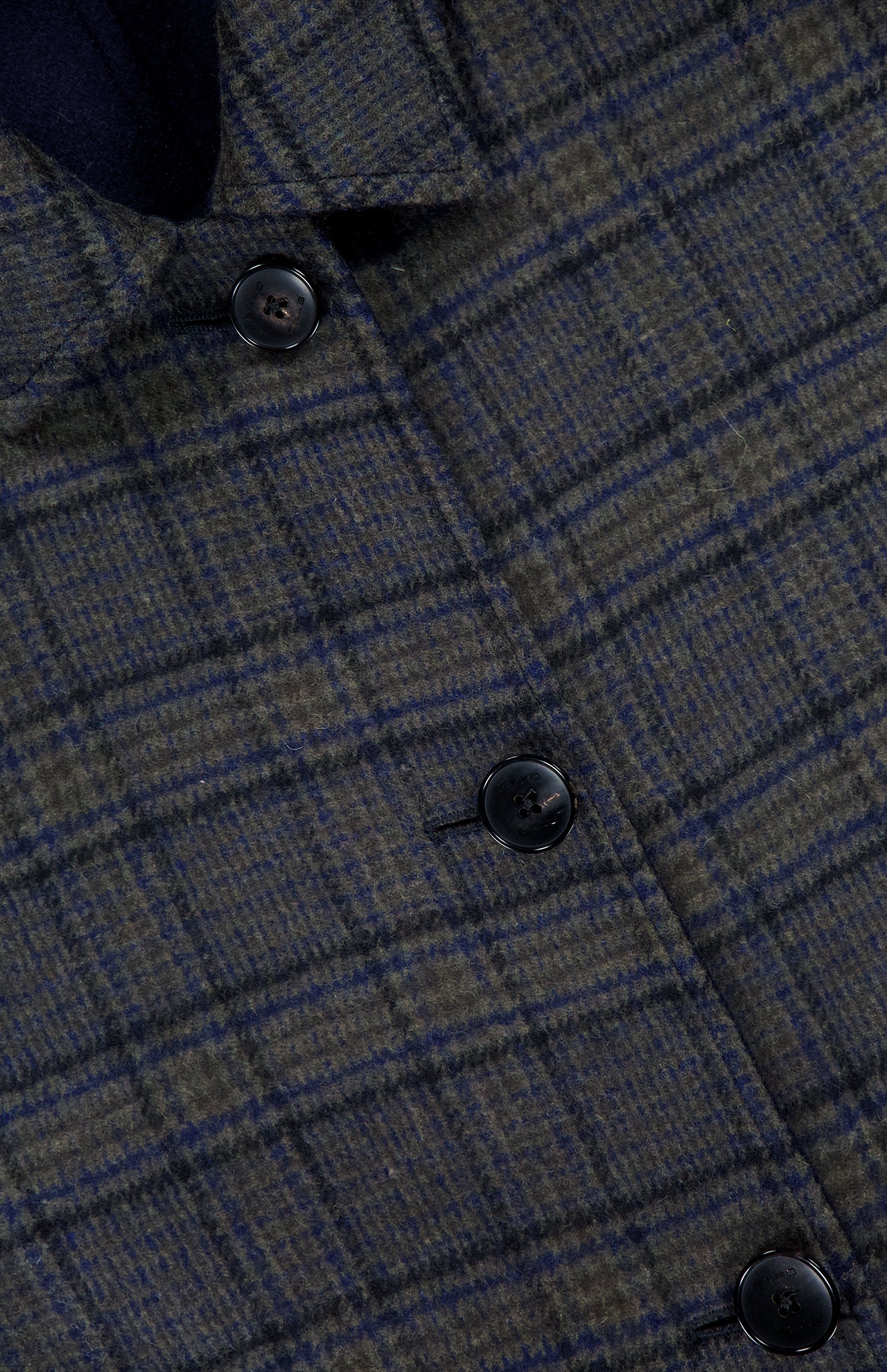 Close-up of the ETRO Plaid Long Reversible Coat, a men’s Italian design crafted from plaid fabric in dark green and navy blue with lighter accents. Four black buttons are arranged in a vertical line, highlighting the texture and rich detail of the material.