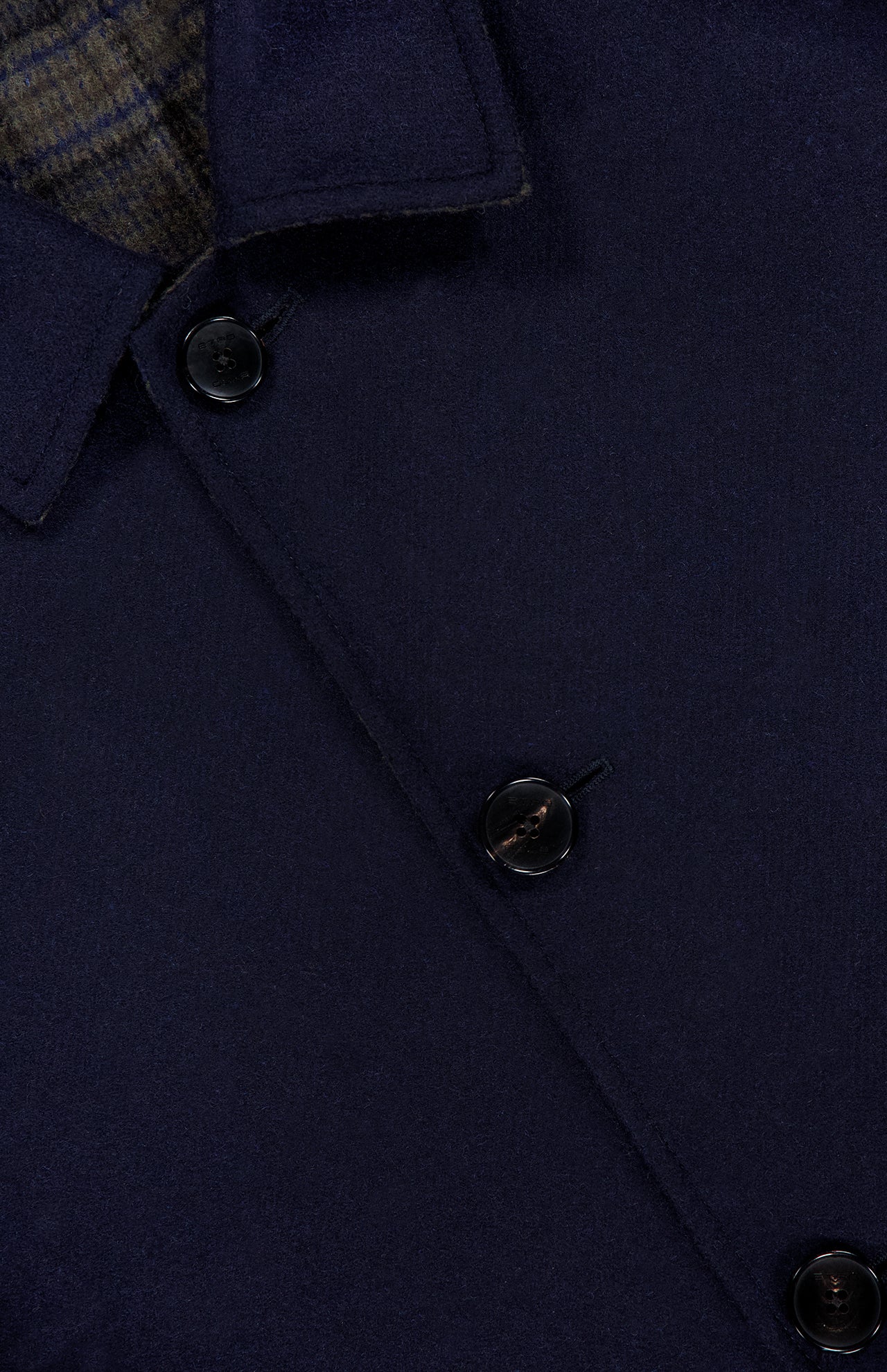 Close-up of the ETRO Plaid Long Reversible Coat in navy wool, featuring three black buttons and part of the collar; a hint of plaid fabric peeks out from beneath the top collar, highlighting the refined detailing characteristic of this men’s Italian coat.
