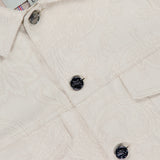 Close-up of ETRO’s Tonal Paisley Print Denim Jacket in cream, showcasing black buttons, flap chest pockets, and a striped collar lining. Made in Italy.
