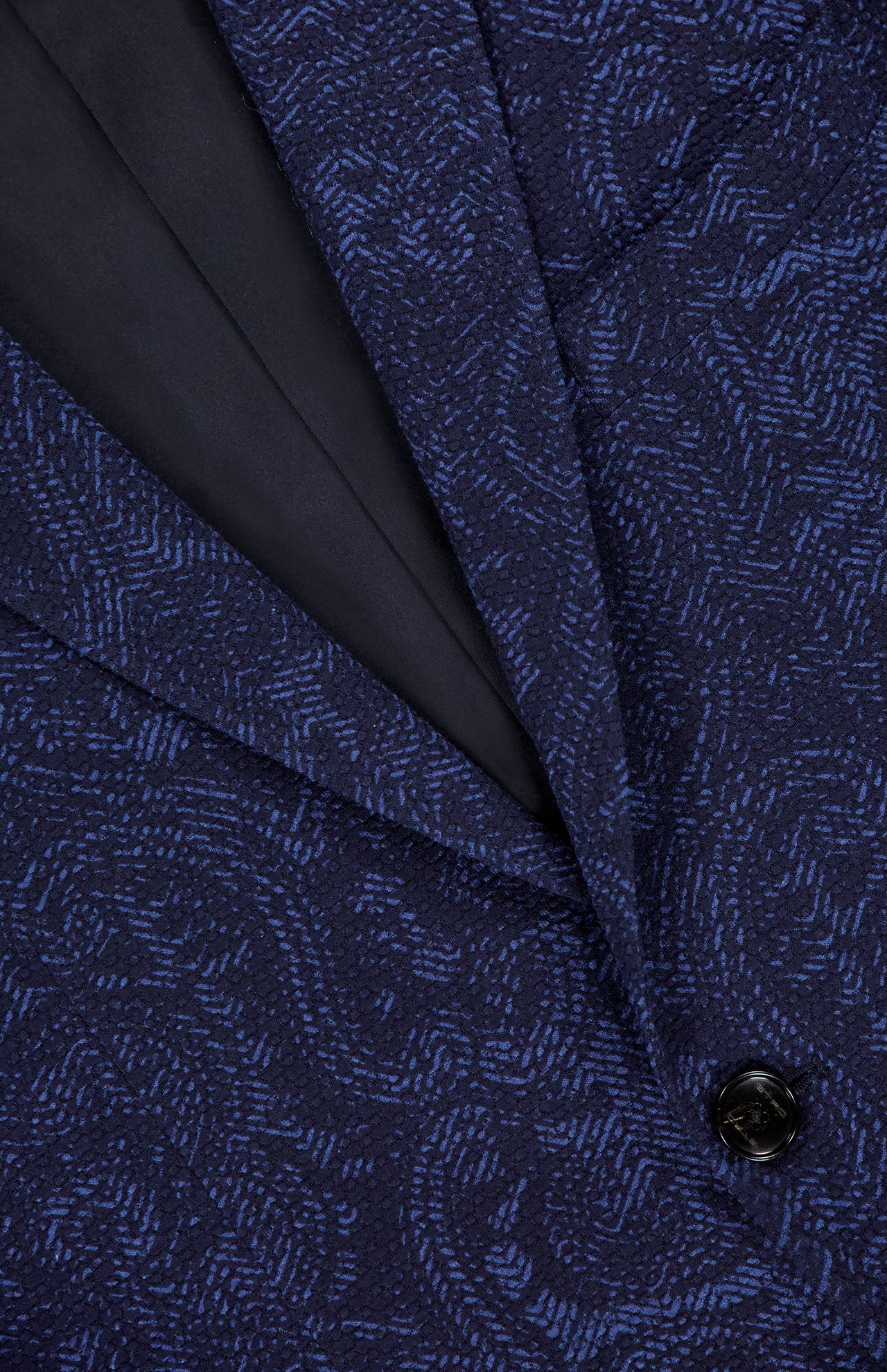 Close-up of the Tonal Paisley Print Sportcoat by ETRO—a luxury statement jacket in dark blue with a subtle paisley pattern, featuring a black button and lapel with black lining detail.