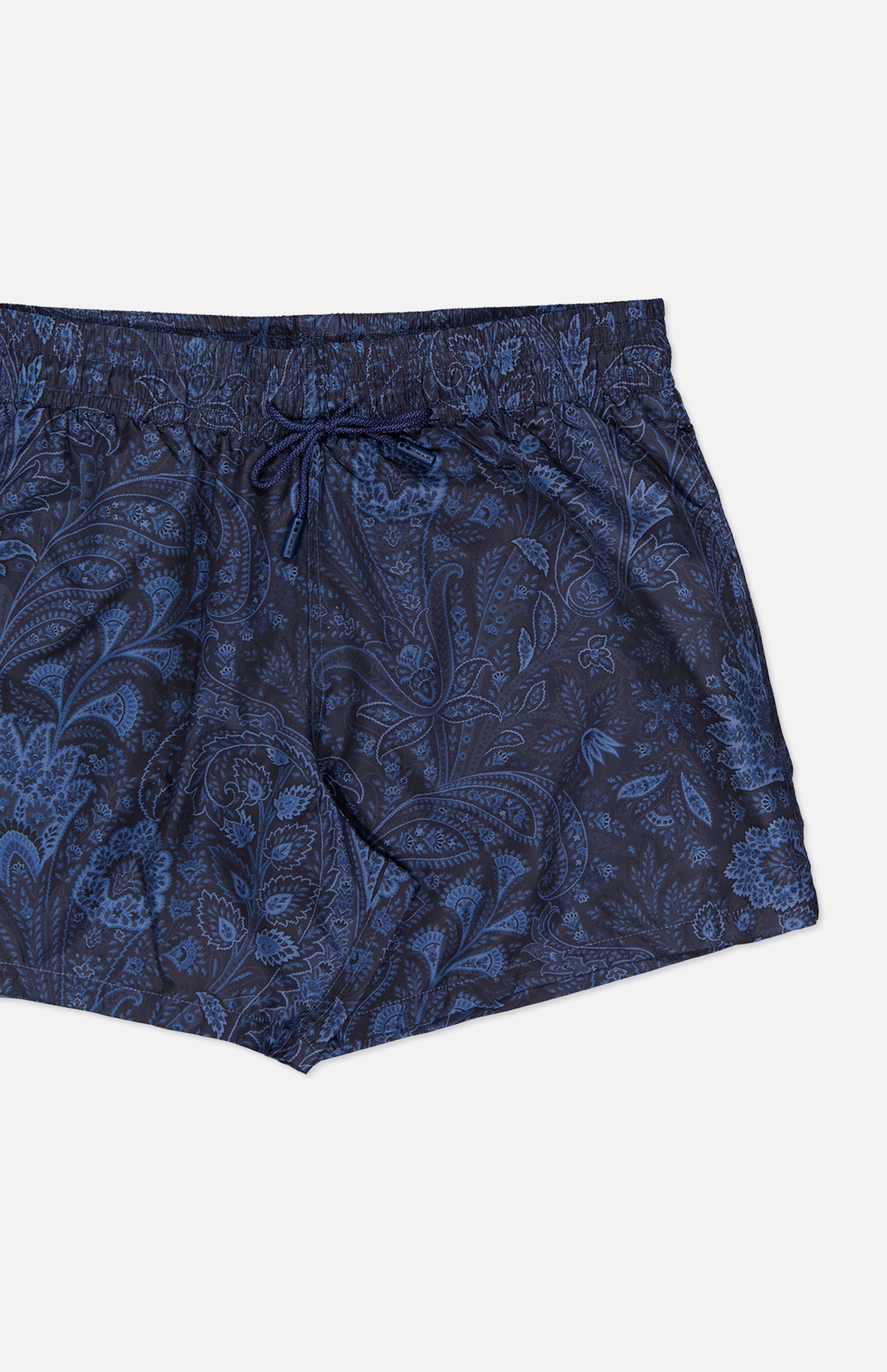 The ETRO Paisley Print Swim Trunk features a subtle paisley design, dark blue color, elastic waistband with drawstring, relaxed fit, and is shown on a plain white background.