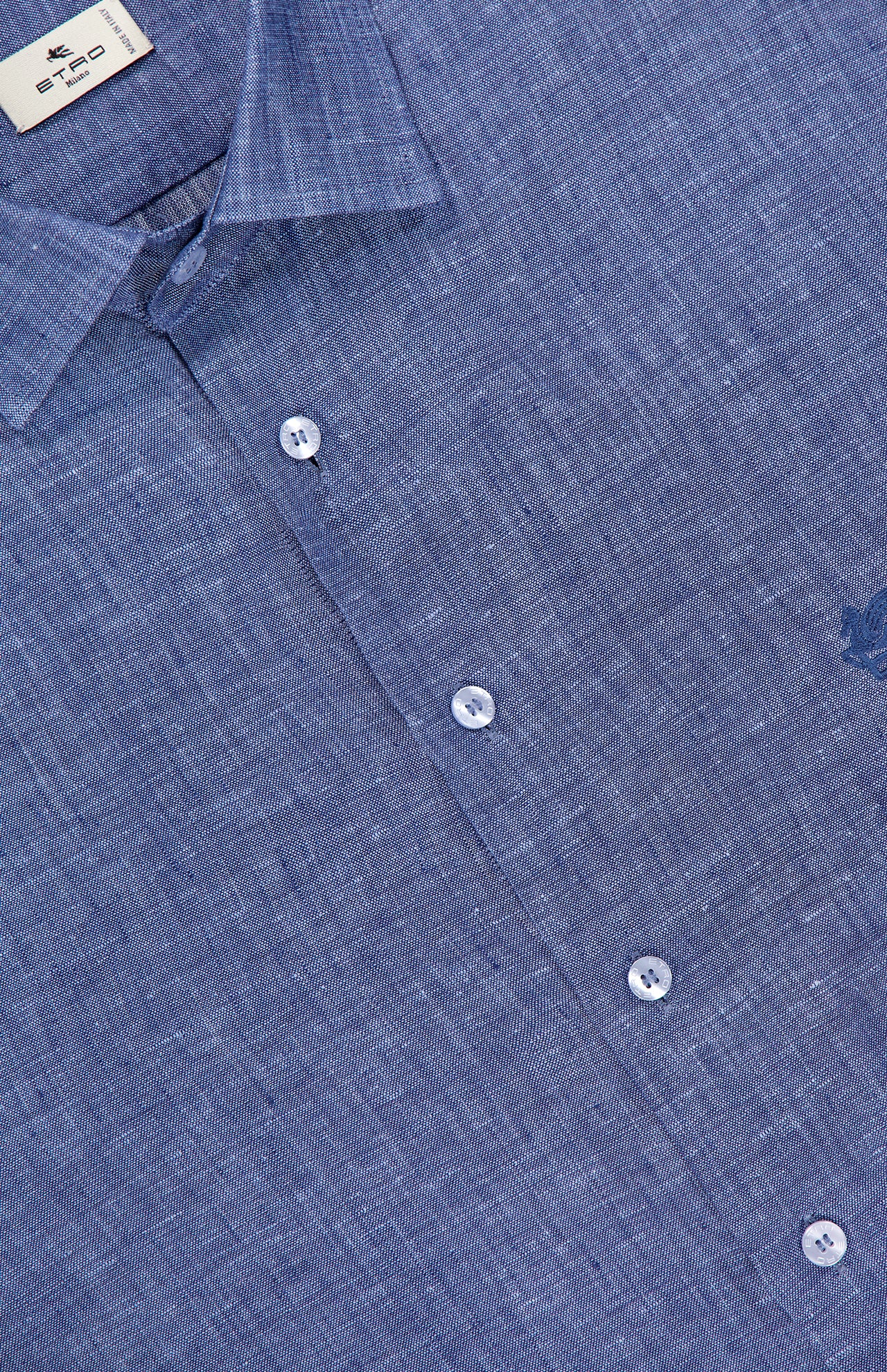 Close-up of the ETRO Roma Long Sleeve Shirt in blue linen, made in Italy, with white buttons, a collar, a visible brand tag at the neckline, subtle texture, and an embroidered logo on the right side.