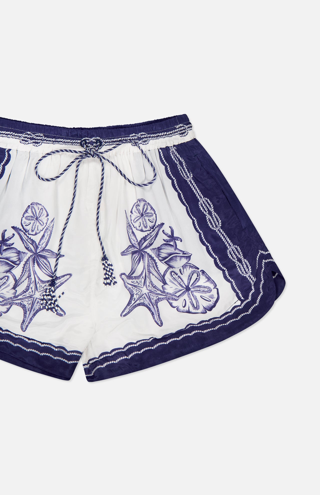 The Coast Scarf Shorts by FARM RIO feature a relaxed fit, drawstring waist, and intricate purple and blue floral and sea star embroidery—perfect for your next coastal vacation.
