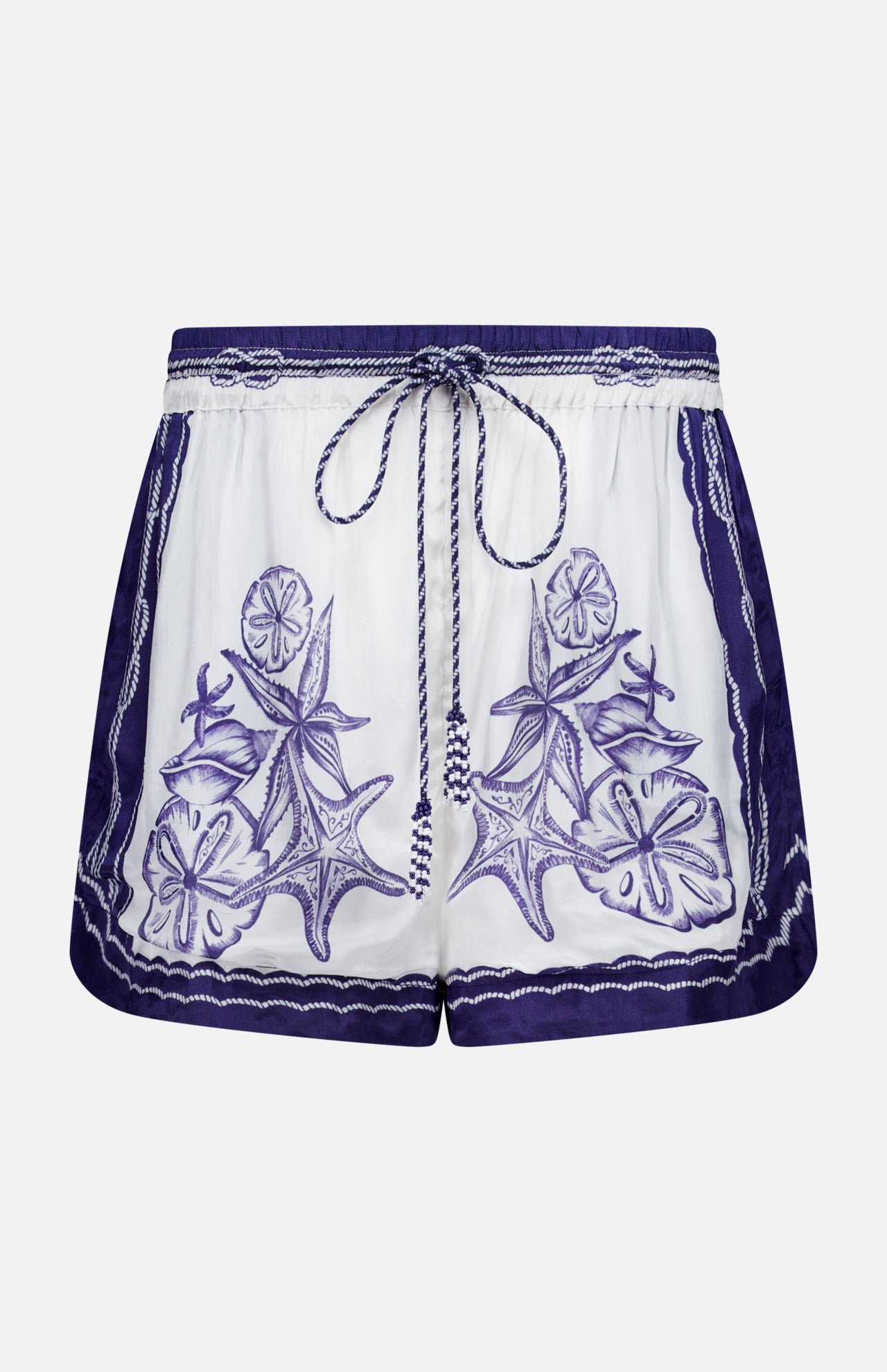 The Coast Scarf Shorts by FARM RIO are white coastal vacation shorts with a navy waistband, blue floral and leaf embroidery on the front, borders, and a braided drawstring tie at the waist.