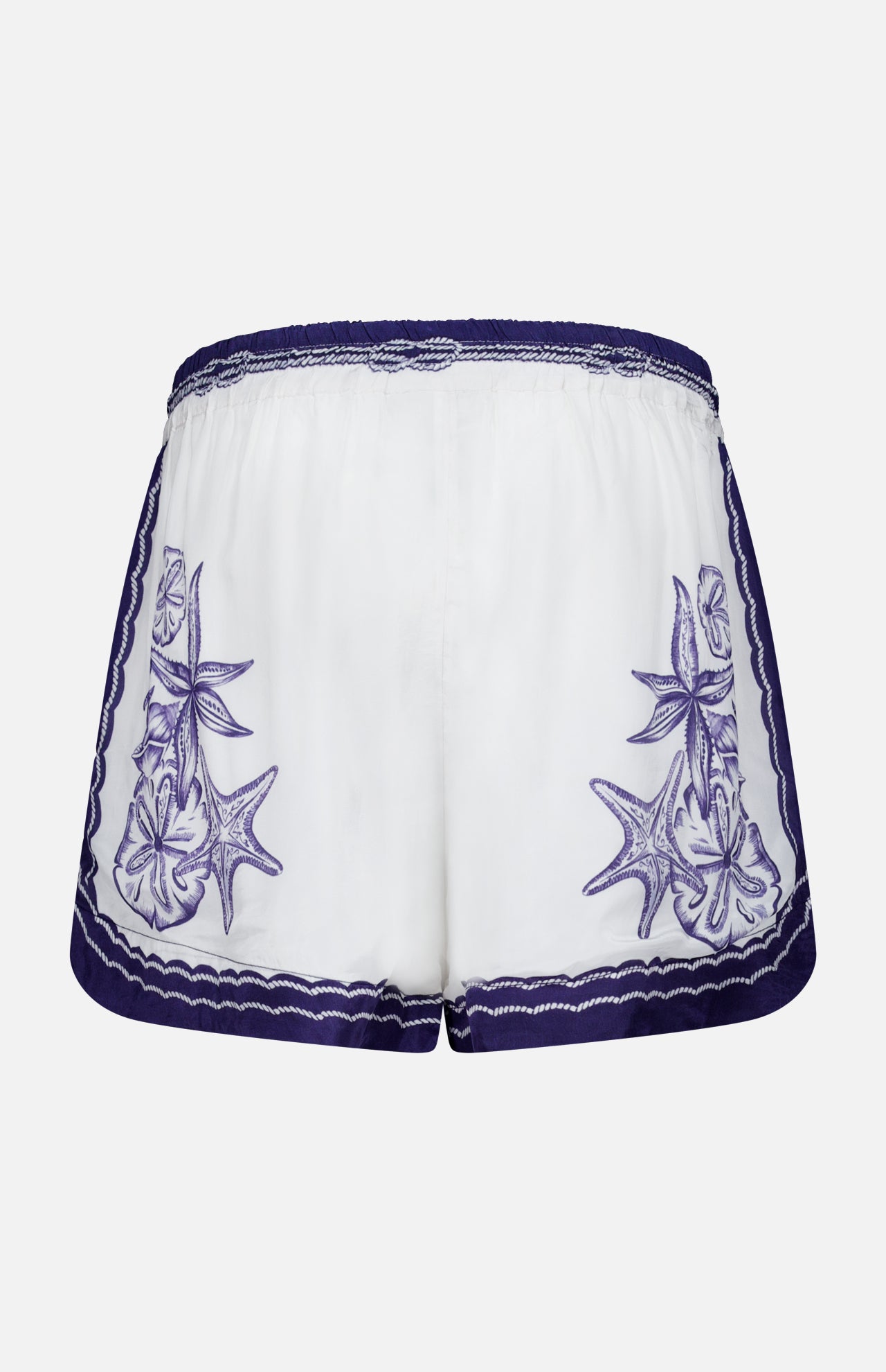 FARM RIO's Coast Scarf Shorts are white coastal vacation shorts with an elastic waistband, purple embroidered seashell and starfish accents on each side, and a purple scalloped trim along the waistband and hem.