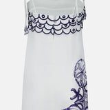 The Coast Stars Linen Mini Dress by FARM RIO is a white sleeveless summer dress with thin shoulder ties, scalloped navy embroidery on top, and navy sea life with starfish and shells—perfect for any coastal party.