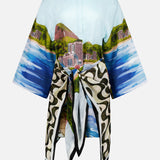 The Copacabana Beach Long Sleeve Kimono by FARM RIO showcases a vibrant coastal landscape with mountains, buildings, and sea, featuring wide sleeves and a colorful waist-tied scarf for added flair.