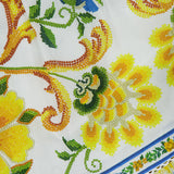 Close-up of the Emily Floral Tapestry Midi Dress by FARM RIO, featuring vibrant yellow, green, and blue floral embroidery on white fabric with blue and green borders—ideal for adding artistic charm to your summer or boho wardrobe.