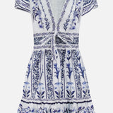 The Flowers Arch Mini Dress by FARM RIO features short sleeves, a v-neckline, white and blue floral patterns, gathered front tie, fitted waist, ruffled hem with piping, and intricate vertical botanical designs for added elegance.