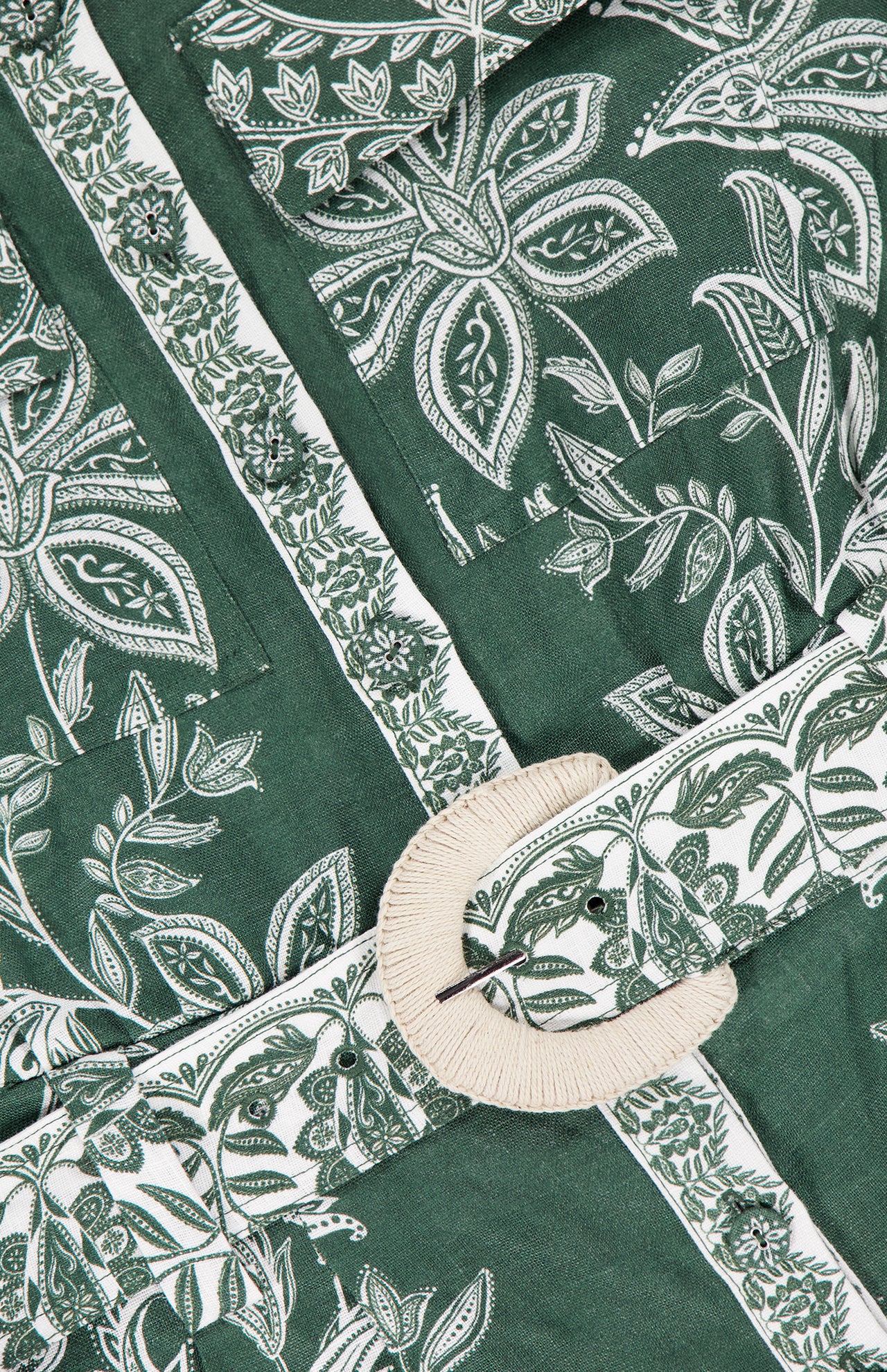 Close-up of the FARM RIO Miranda Short Sleeve Belted Romper, featuring green tropical floral and leaf prints, a belted waist with a round off-white woven buckle, intricate designs, and detailed stitching.