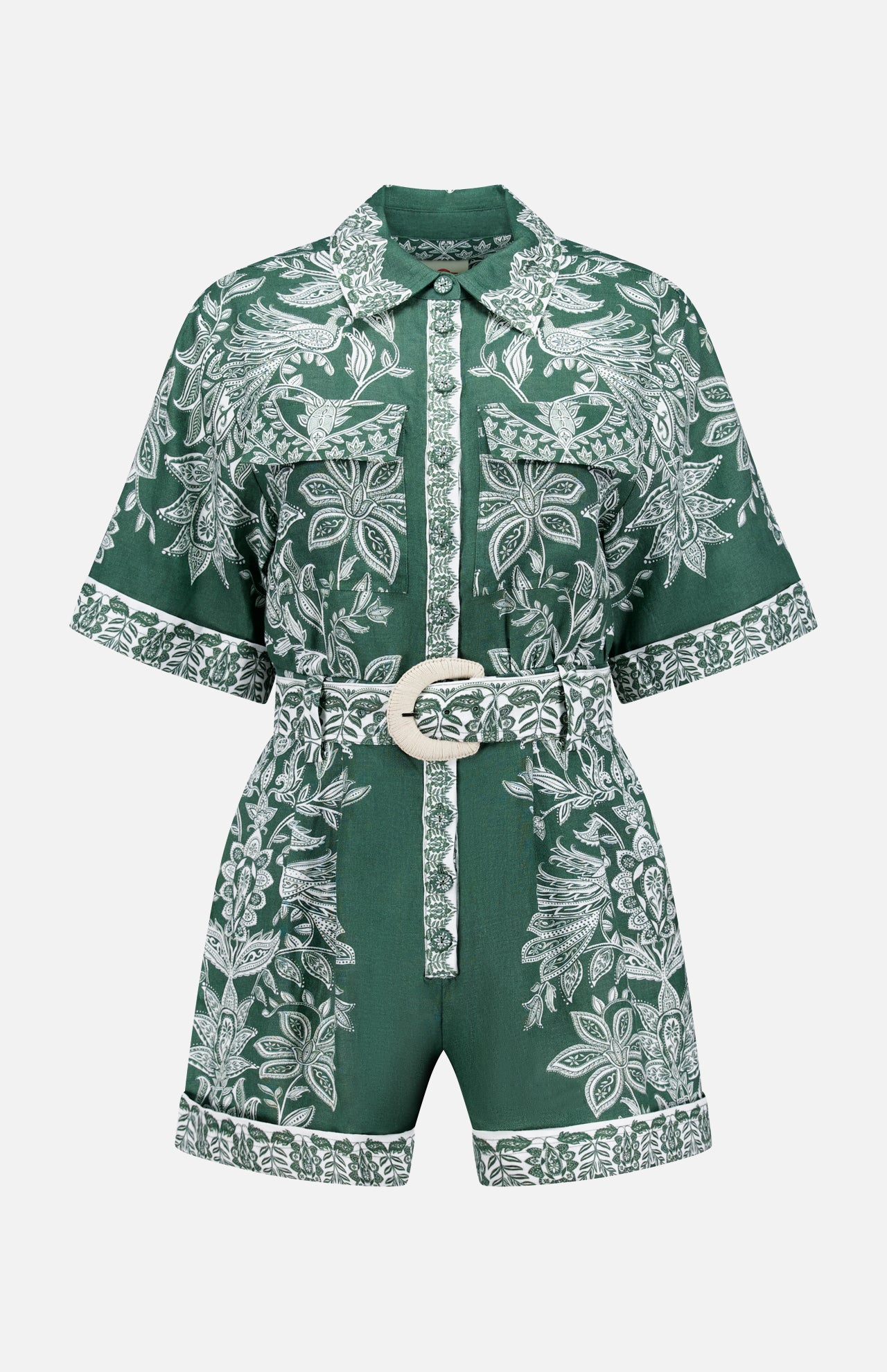 The Miranda Short Sleeve Belted Romper by FARM RIO features green fabric with white floral patterns, a collared neckline, front buttons, and a matching belt with a round buckle. Floral trim accents the hem and button placket.