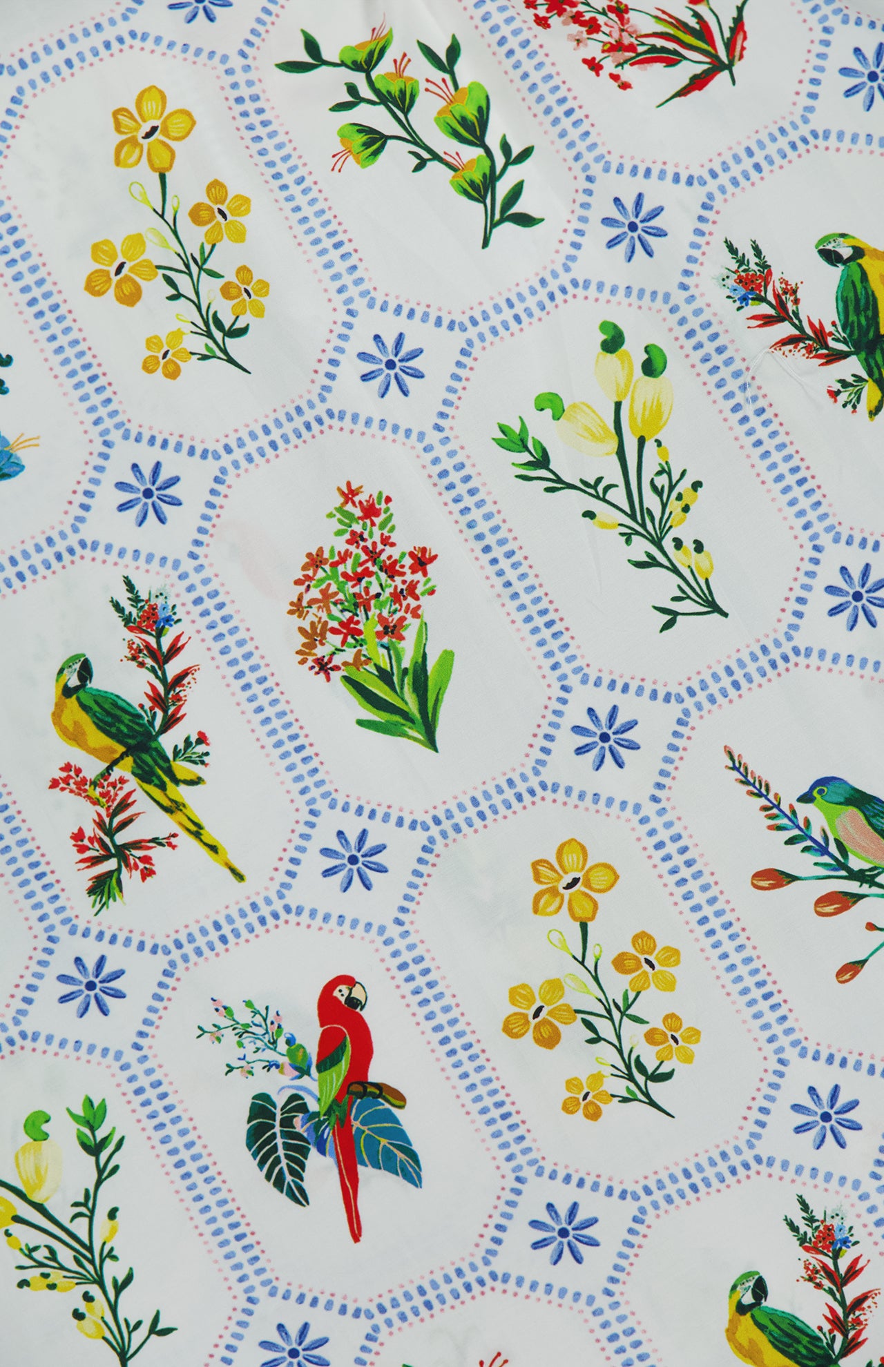The FARM RIO Tropical Porcelain Maxi Dress features colorful parrots, yellow flowers, and green leaves in blue dotted hexagons on white cotton.
