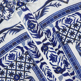 Close-up of the FARM RIO Wonderful City Linen Romper, featuring blue and white nature-inspired patterns and blue buttons down the front, with a fabric tag inside the collar reading FARM RIO.