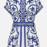 The FARM RIO Wonderful City Linen Romper is a short-sleeved, belted linen piece with a blue and white tropical palm tree and geometric design, intricate nature-inspired patterns, and a tailored fit seen from the back.
