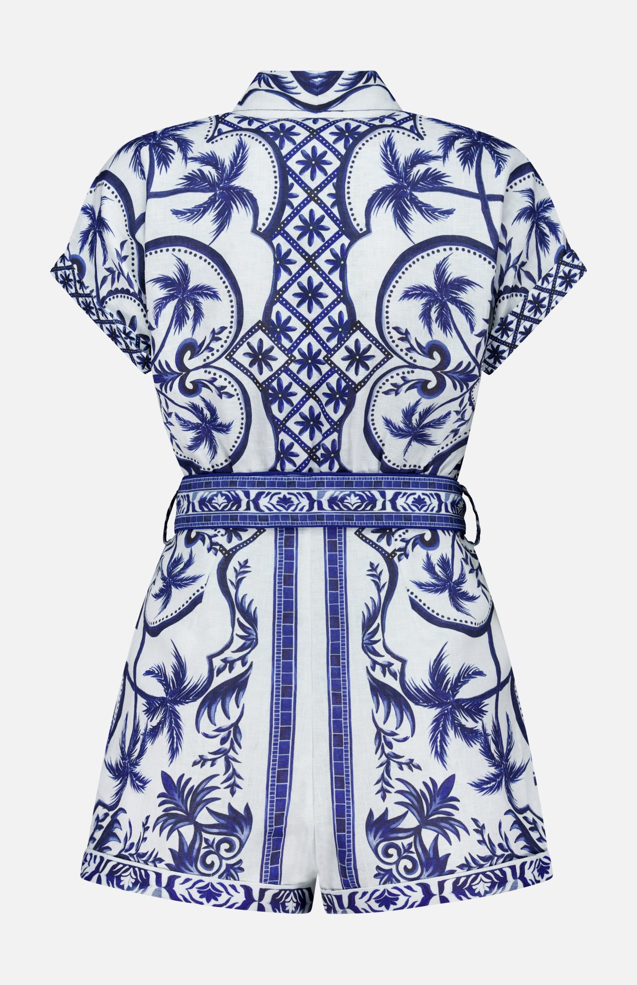 The FARM RIO Wonderful City Linen Romper is a short-sleeved, belted linen piece with a blue and white tropical palm tree and geometric design, intricate nature-inspired patterns, and a tailored fit seen from the back.