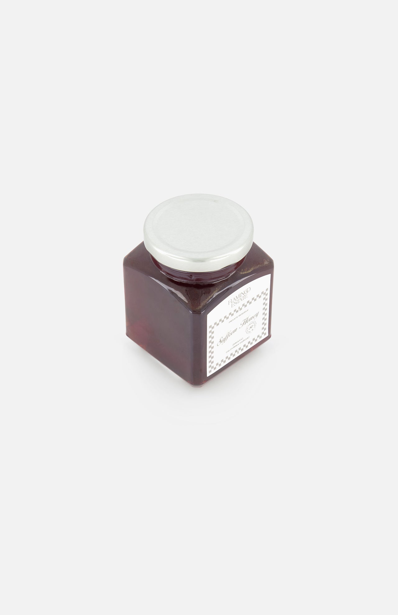 A square glass jar of FLAMINGO ESTATE's Golden Saffron Honey, topped with a white lid and front label in their signature style, sits on a plain white background.