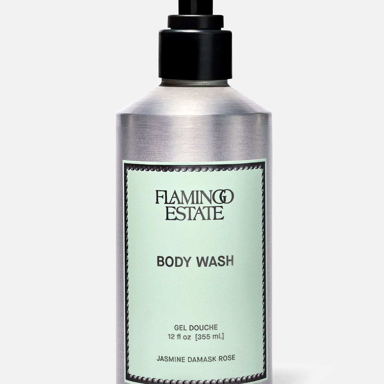 A silver pump bottle of FLAMINGO ESTATE Jasmine Damask Rose Body Wash with a light green label and BODY WASH text, infused with natural sea salt, is shown against a plain light background.