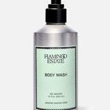 A silver pump bottle of FLAMINGO ESTATE Jasmine Damask Rose Body Wash with a light green label and BODY WASH text, infused with natural sea salt, is shown against a plain light background.