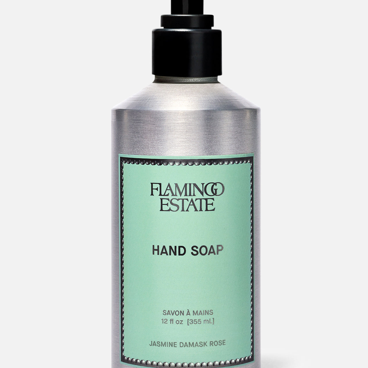 A silver pump bottle of FLAMINGO ESTATE Jasmine Damask Rose Hand Soap, with a mint green label featuring black text and a decorative border. The label highlights nourishing rosehip seed oil. The background is plain light gray.