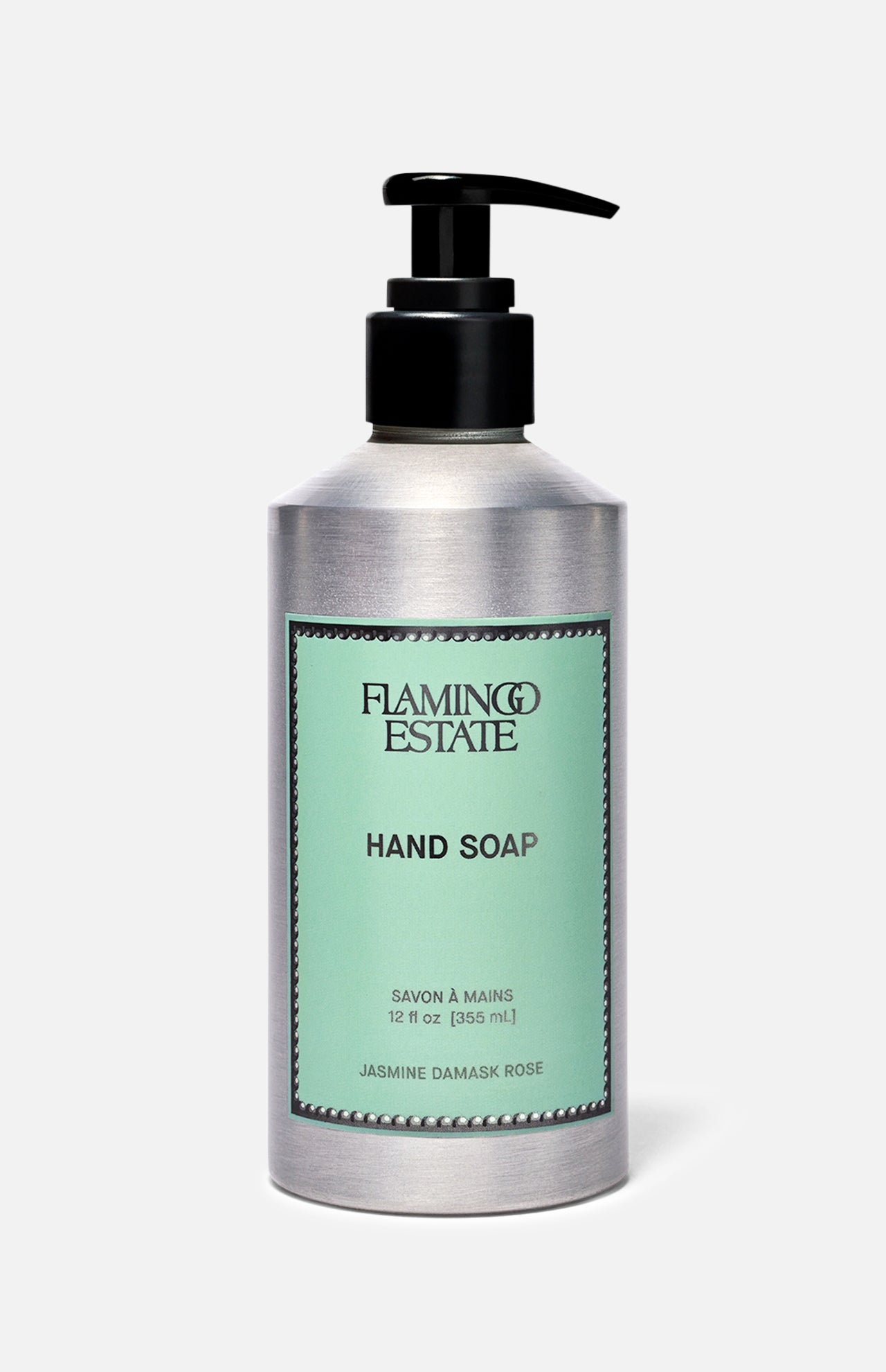 A silver pump bottle of FLAMINGO ESTATE Jasmine Damask Rose Hand Soap, with a mint green label featuring black text and a decorative border. The label highlights nourishing rosehip seed oil. The background is plain light gray.