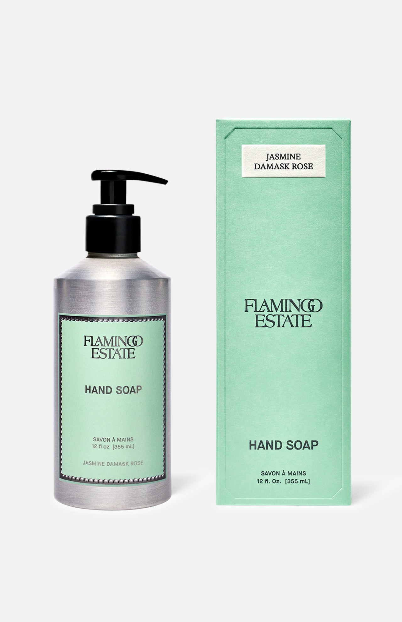 A silver pump bottle of FLAMINGO ESTATE Jasmine Damask Rose Hand Soap stands beside its matching green box, both featuring minimalist black text and enriched with nourishing rosehip seed oil on a light green background.