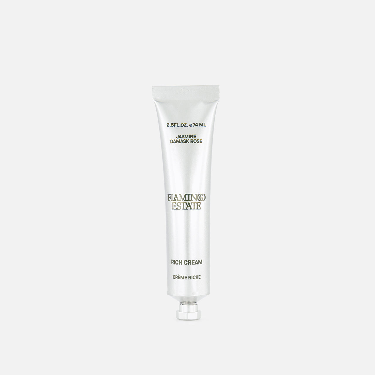 A silver tube labeled FLAMINGO ESTATE Jasmine Damask Rose Rich Cream, enriched with shea butter, stands upright on a plain white background, with text appearing above and below the product.