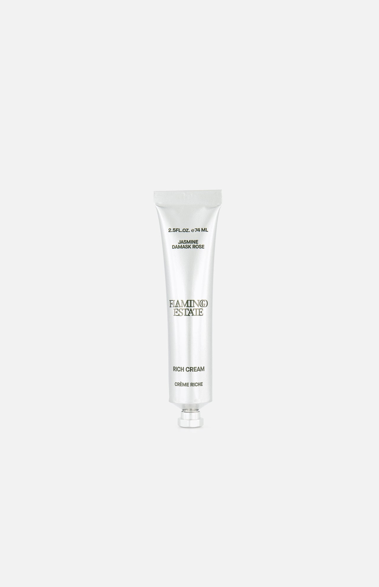 A silver tube labeled FLAMINGO ESTATE Jasmine Damask Rose Rich Cream, enriched with shea butter, stands upright on a plain white background, with text appearing above and below the product.