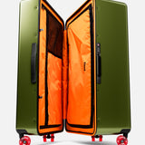 The Bold Suitcase by FLOYD is a large, open hard-top case in olive green with a bright orange interior, black mesh pockets, and red skateboard spinner wheels, shown upright against a white background.