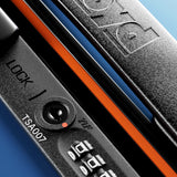 Close-up of The Cabin Suitcase by FLOYD—black hard-top design with orange accents, TSA lock, and zipper pull—set against a blue background.