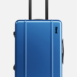 The Cabin Suitcase by FLOYD features a blue hard-top shell, black telescopic handle, two red skateboard spinner wheels, side handle, TSA lock, and a small black logo near the top—all set against a plain white background.