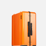The Cabin Suitcase by FLOYD stands upright against a plain light background, featuring a bright orange hard-top shell, black handle, combination lock, and four red transparent skateboard spinner wheels. Cabin-approved size for overhead compartments.