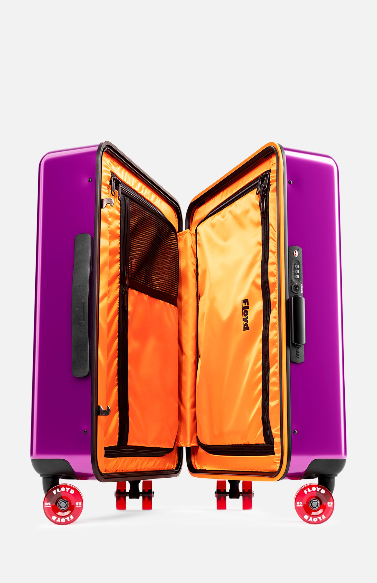 The Cabin Suitcase by FLOYD is a purple hard-top case with black handles, a built-in TSA lock, and red skateboard-style wheels. Open it to reveal a bright orange interior with zippered compartments for organized travel.