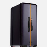 The FLOYD Check-In Suitcase stands upright against a plain light background, featuring a sleek dark purple hard-top, yellow accent stripe, black handle, TSA lock, and four transparent red 360° spinner wheels.