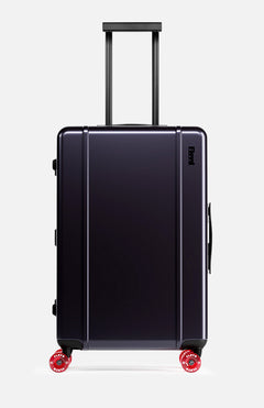 The Check-In Suitcase by FLOYD features a hard-top design in a dark hue, TSA lock, telescoping handle, and four red 360° spinner wheels. It is pictured upright against a plain light background.