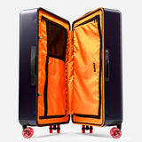 The Check-In Suitcase by FLOYD is a hard-top case with a dark exterior and bright orange interior, open to show mesh and zippered compartments. It features 360° spinner wheels and a built-in TSA lock for secure travel.