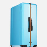 The FLOYD Check-In Suitcase, featuring a light blue hard shell, black handle, orange center stripe, and four transparent red 360° spinner wheels, is shown upright on a plain white background.